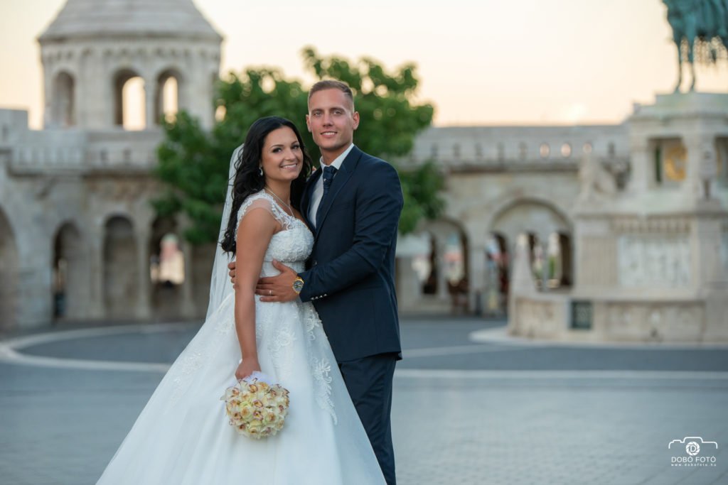 Kreatív esküvői fotózás - Debrecen. A Halászbástya romantikus hangulata adja a háttérszínt ehhez a kreatív esküvői fotóhoz Budapesten. Az ifjú pár elegáns megjelenése és boldog mosolya tökéletesen harmonizál a helyszín varázslatos atmoszférájával, amely a város egyik legikonikusabb helyszíne esküvői fotózáshoz.