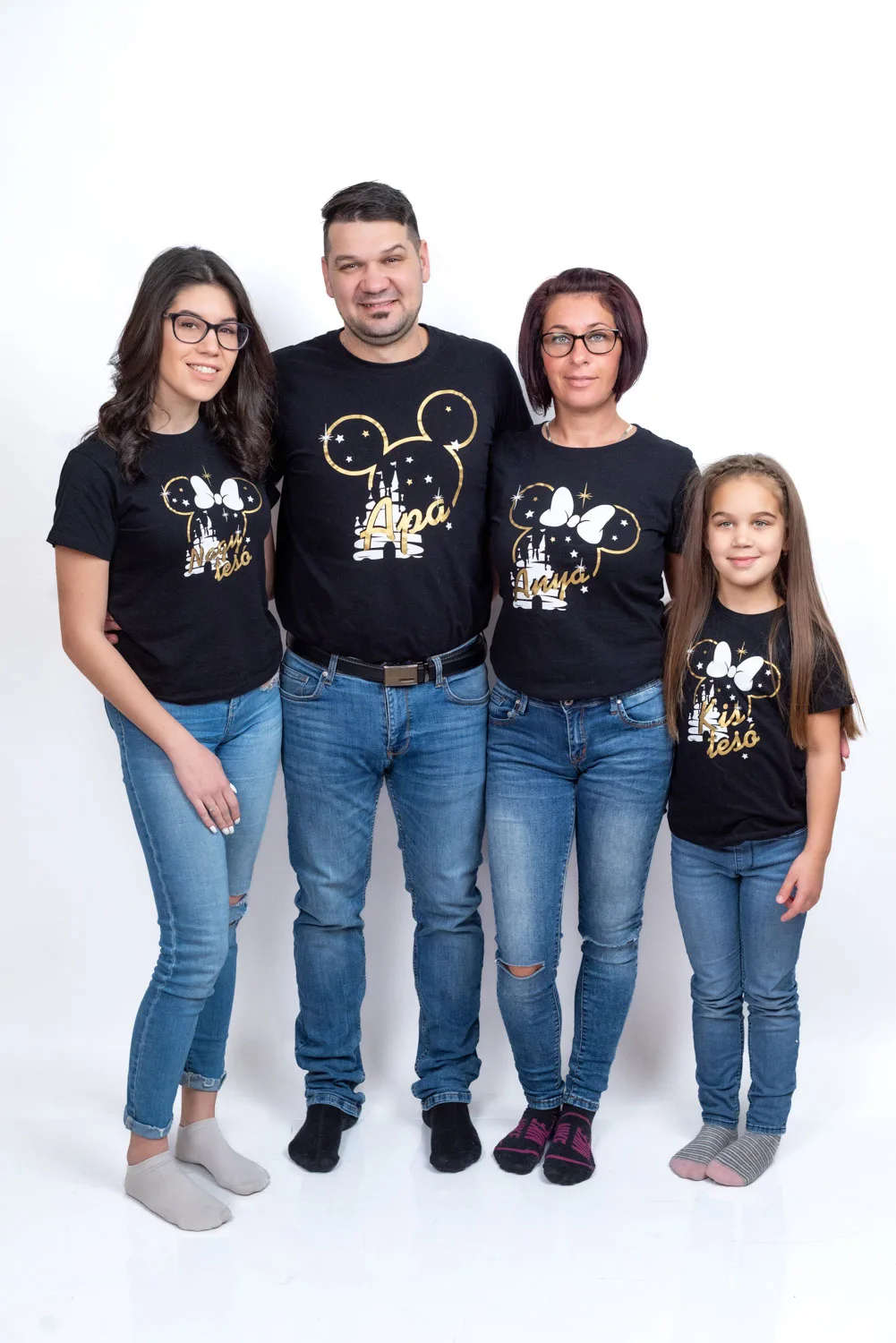 Debreceni családi fotózás négytagú családdal, fekete pólóban és farmerben, fehér stúdióháttér előtt állva.