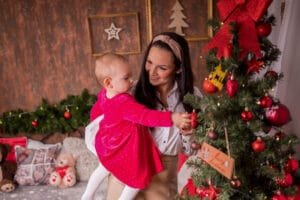 Anya és kislánya együtt díszítik a karácsonyfát ünnepi dekorációval körülvéve, meghitt karácsonyi pillanat Debrecenben.