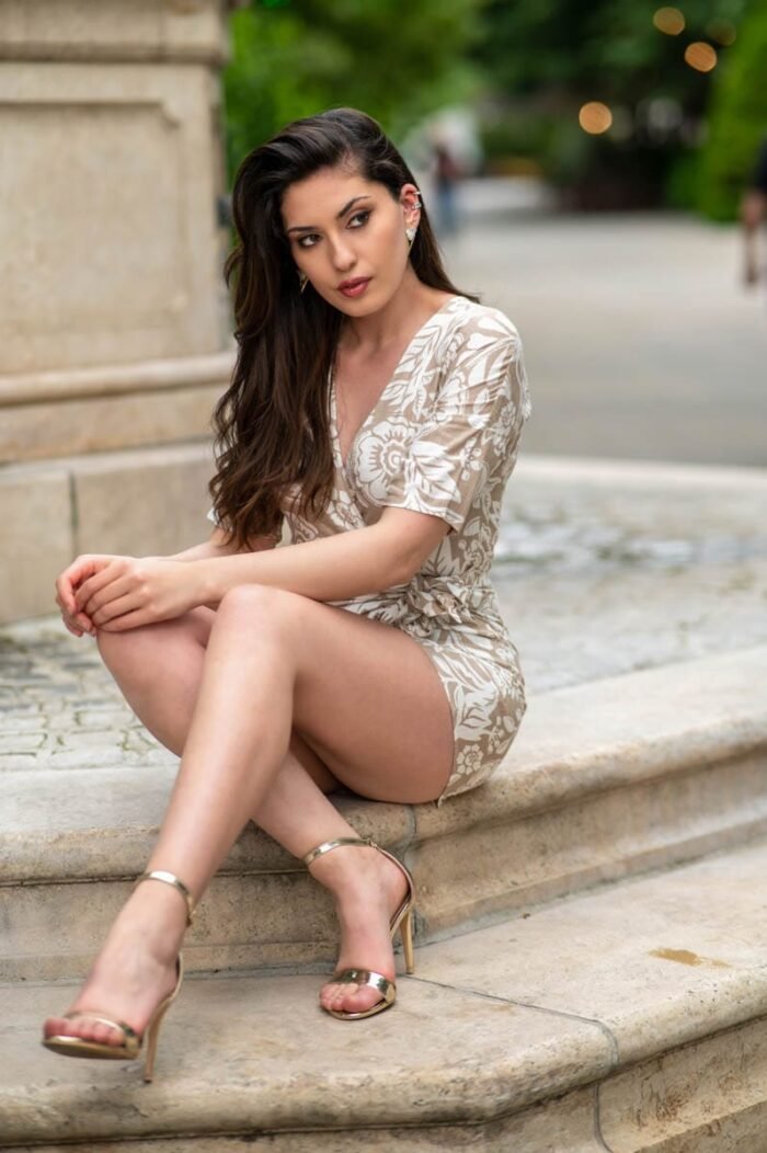 Modell: Horváth Krisztina, mintás ruhában, arany szandálban ül egy kőlépcsőn, városi háttérrel, Debrecenben készült portréfotó