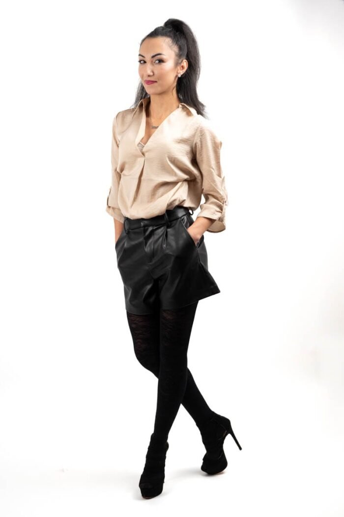 Debreceni stúdió fotózás, fiatal nő elegáns bézs blúzban, fekete bőrnadrágban és csipkés harisnyában, fehér háttérrel.
