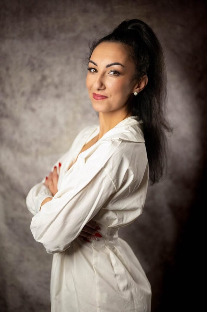 Debreceni stúdióban készült portré, elegáns nő fehér ingben, kifinomult stílusú háttérrel.
