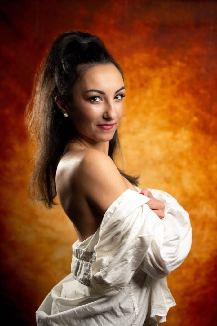 Portréfotó Debrecen stúdiójában, meleg színű háttérrel, finom megvilágítással, mosolygó modell