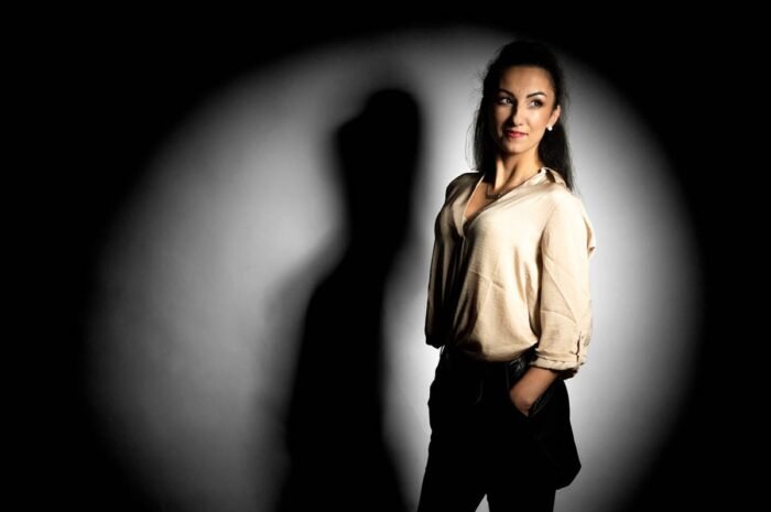 Portréfotó árnyékos háttérrel, művészi megvilágítással Debrecen stúdiójában, elegáns modell természetes pózban.