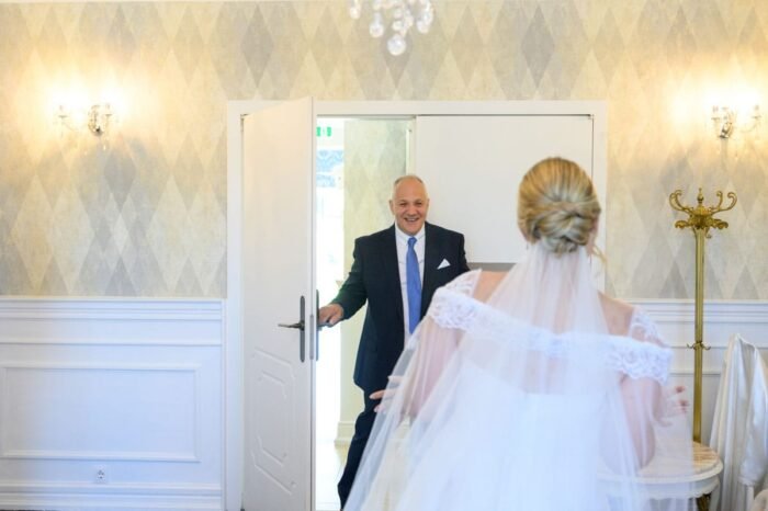 A menyasszony és édesapja meghitt pillanatban osztoznak, amikor az apa először látja lányát menyasszonyi ruhában, érzelmekkel teli mosollyal és könnyekkel a szemében.