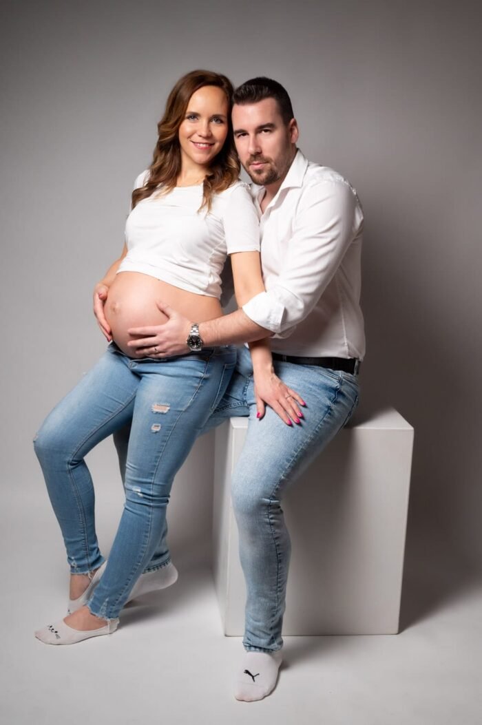 Kismama fotózás Debrecenben, boldog pár közös képe stúdióban, világos és hangulatos megvilágítással.