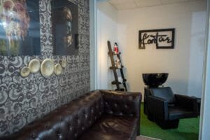 A Kontur szalon várótere, elegáns bőr kanapéval, dekoratív fali díszekkel és modern bútorokkal. A helyiséget a "Kontúr" feliratú falikép és a letisztult, minimalista design jellemzi, ami kellemes hangulatot biztosít a vendégeknek.