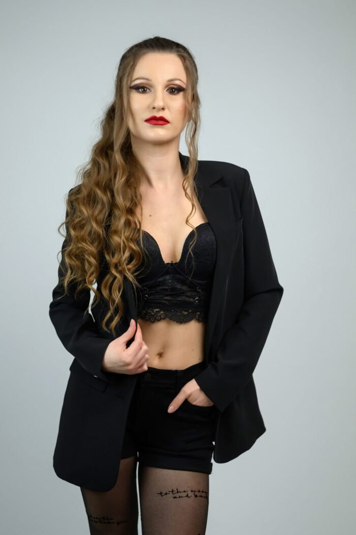 Fiatal nő elegáns fekete ruhában, modern portréfotózás Debrecenben, amely kiemeli a magabiztosságot és a karakteres stílust.