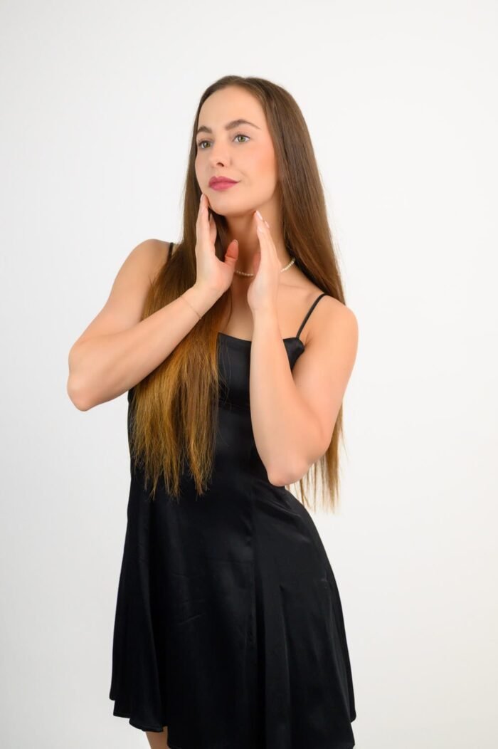 Fotózás Debrecenben - Egy elegáns portré egy fekete ruhás modellről, fehér háttér előtt, stúdióban készítve.