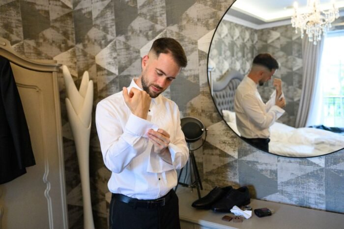 A vőlegény elegánsan igazítja az ingujját a Le Til Kúria egyik szobájában. A tükör visszatükrözi az előkészületek pillanatát, miközben az asztalon gondosan elrendezett kiegészítők láthatók, amelyek az esküvő stílusát tükrözik.