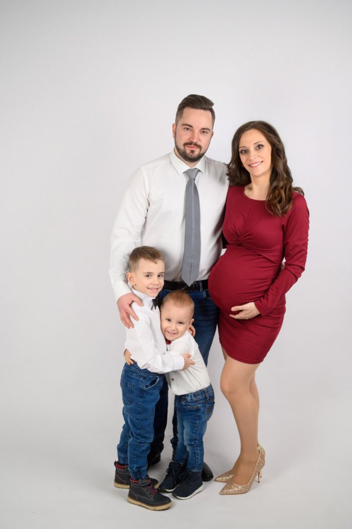 Várandós családi fotózás Debrecen, ahol a kismama, apuka és gyermekeik együtt ünneplik a babavárás örömét. Profi babaváró fényképezés meghitt hangulatban, stúdiókörnyezetben.